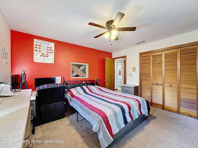 bedroom featuring light carpet, a textured ceiling, visible vents, and a closet