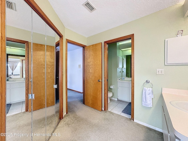 bathroom with carpet floors, visible vents, a textured ceiling, and vanity