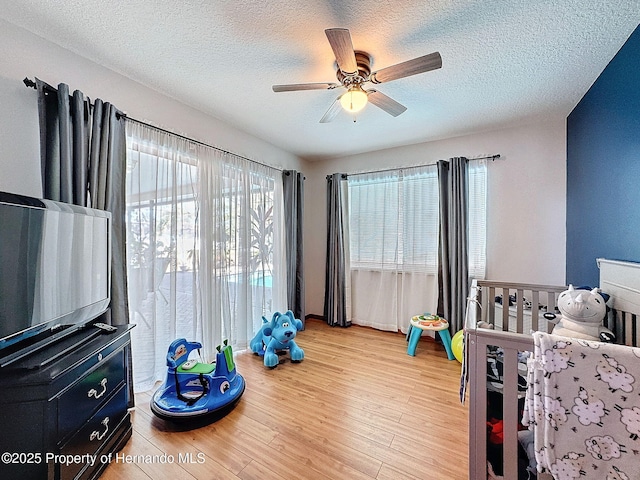 bedroom with light wood-style floors, a textured ceiling, and a ceiling fan