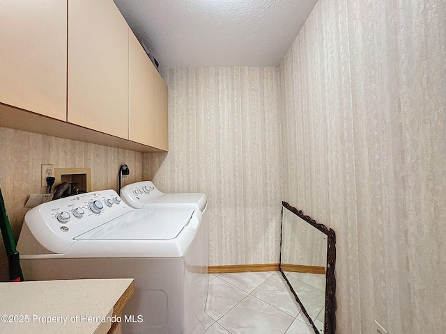 laundry area featuring a textured ceiling, separate washer and dryer, and cabinet space