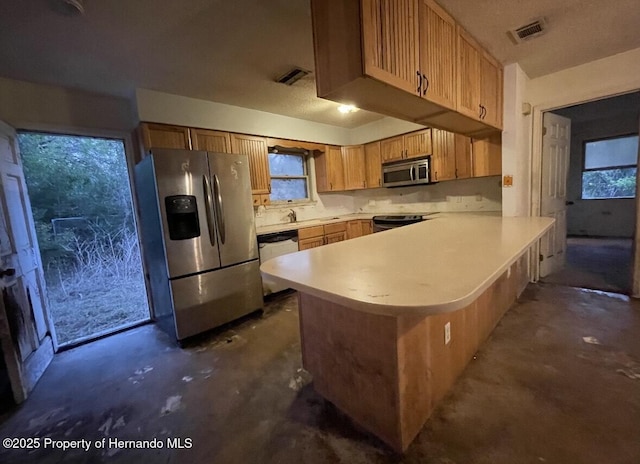 kitchen with visible vents, light countertops, appliances with stainless steel finishes, unfinished concrete floors, and a peninsula