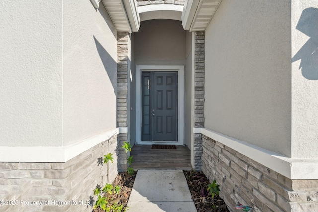 entrance to property with stone siding and stucco siding