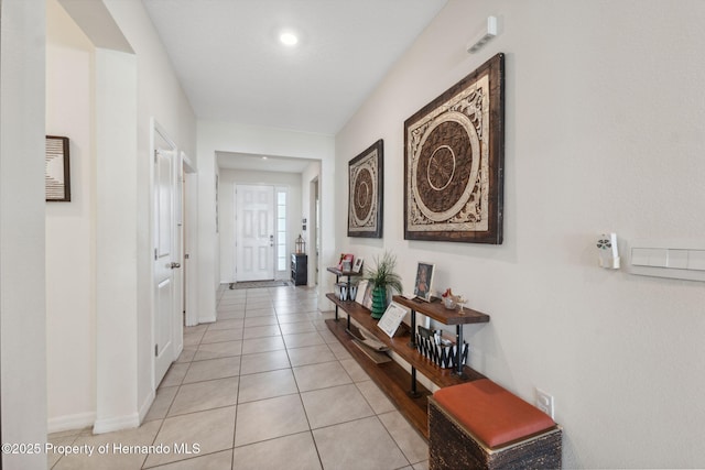 hall featuring light tile patterned flooring and baseboards