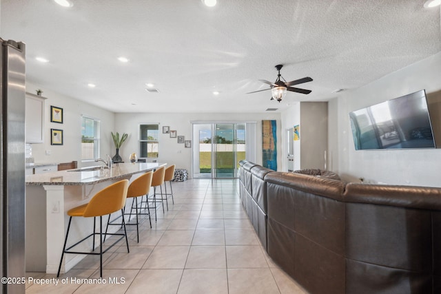 living area featuring a textured ceiling, light tile patterned flooring, a wealth of natural light, and a ceiling fan