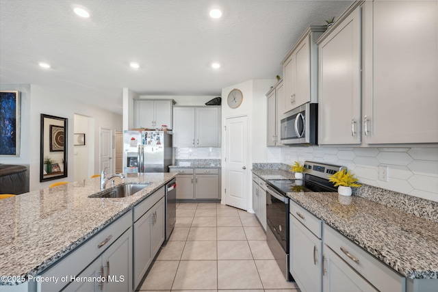 kitchen featuring tasteful backsplash, appliances with stainless steel finishes, gray cabinetry, a sink, and light tile patterned flooring