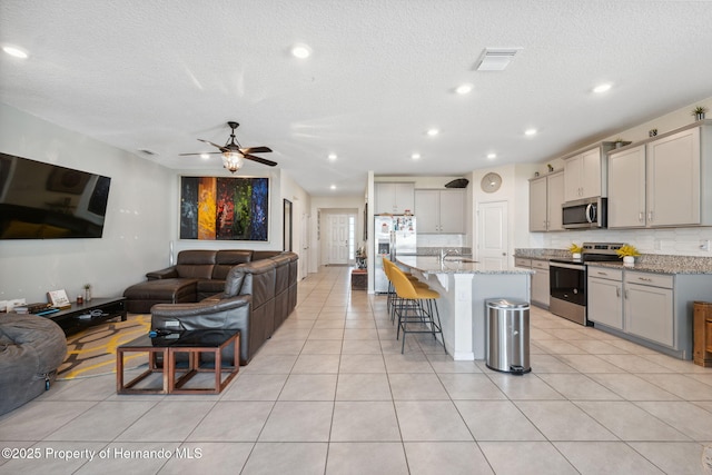 kitchen with light tile patterned floors, stainless steel appliances, a sink, visible vents, and open floor plan