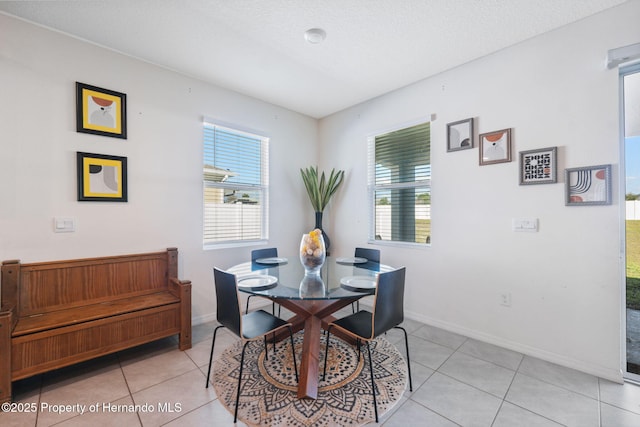 dining space featuring a healthy amount of sunlight, light tile patterned floors, baseboards, and a textured ceiling