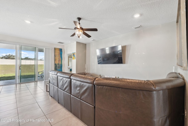 living room with a ceiling fan, visible vents, a textured ceiling, and light tile patterned floors