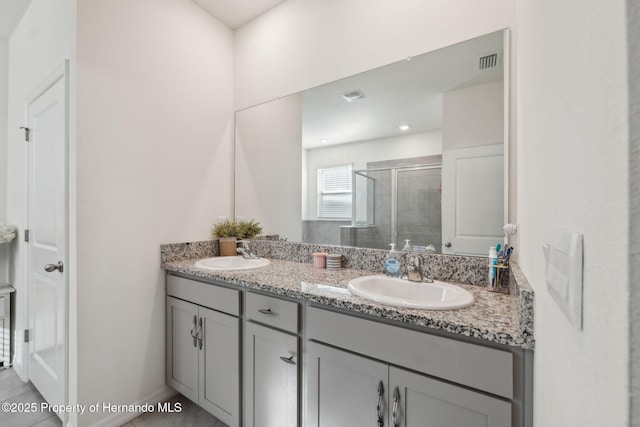 bathroom with double vanity, a stall shower, visible vents, and a sink