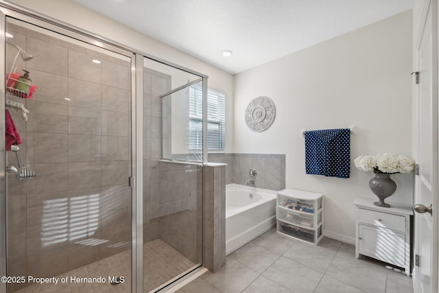 full bath featuring a textured ceiling, tile patterned flooring, baseboards, a shower stall, and a bath