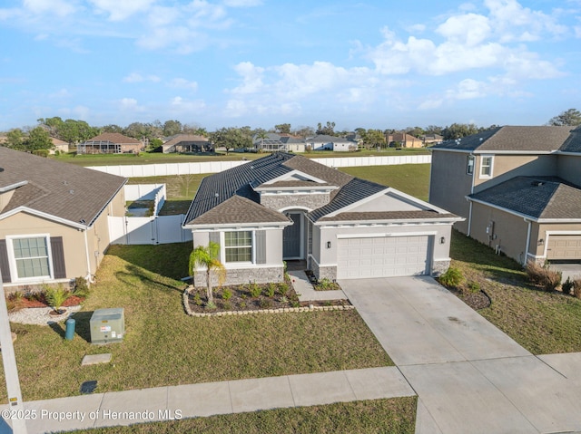 view of front of home featuring driveway, a residential view, an attached garage, fence, and a front lawn