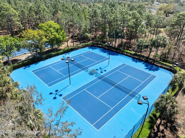 view of sport court featuring fence and a forest view