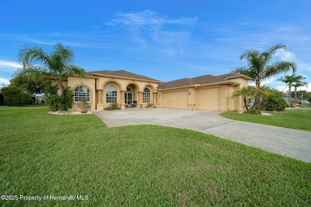 mediterranean / spanish home featuring a garage, concrete driveway, a front yard, and stucco siding