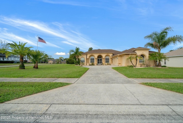 mediterranean / spanish home with a front yard, an attached garage, driveway, and stucco siding