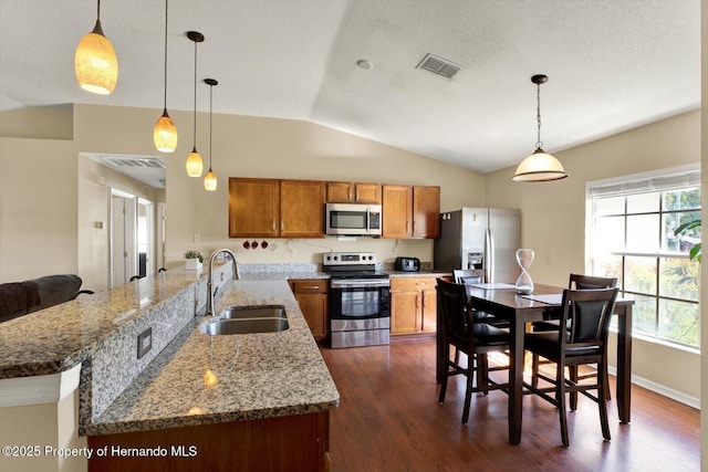 kitchen with visible vents, dark wood-type flooring, a sink, appliances with stainless steel finishes, and brown cabinetry