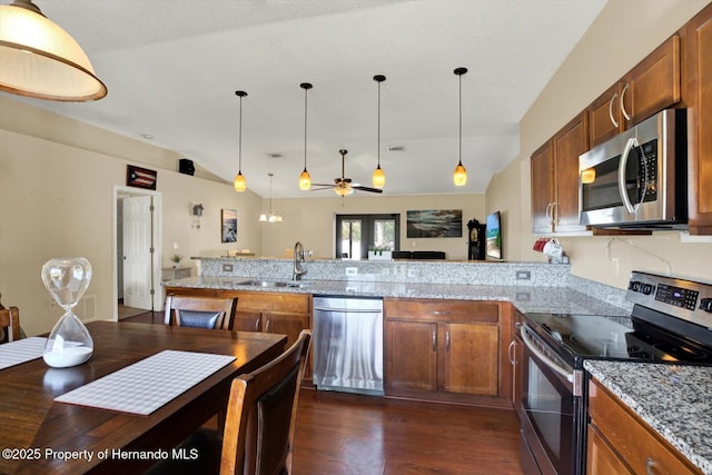 kitchen featuring lofted ceiling, a peninsula, a sink, stainless steel appliances, and pendant lighting