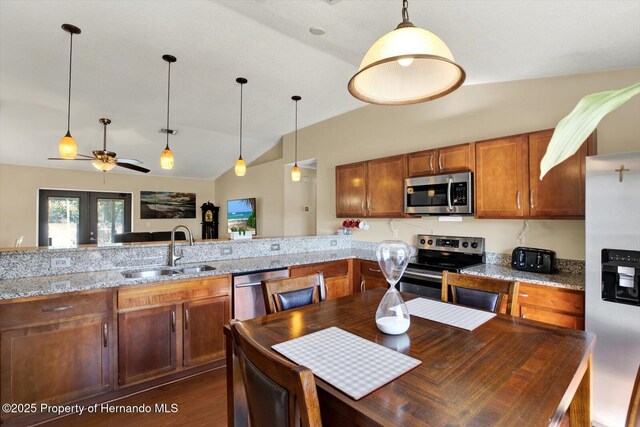 kitchen featuring ceiling fan, pendant lighting, brown cabinetry, stainless steel appliances, and a sink