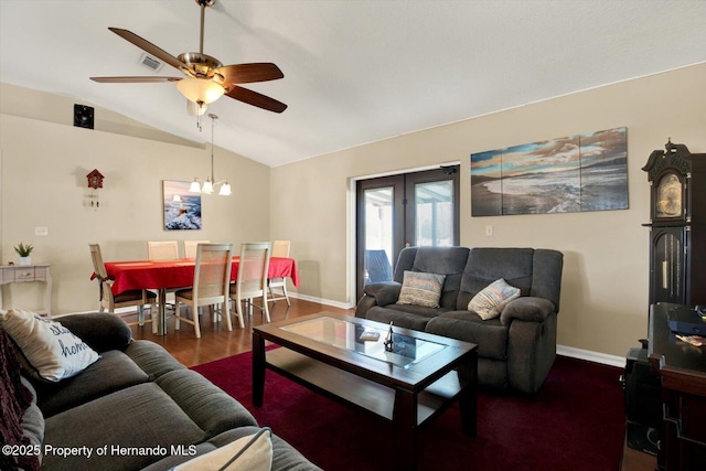 living area featuring baseboards, lofted ceiling, wood finished floors, and ceiling fan with notable chandelier