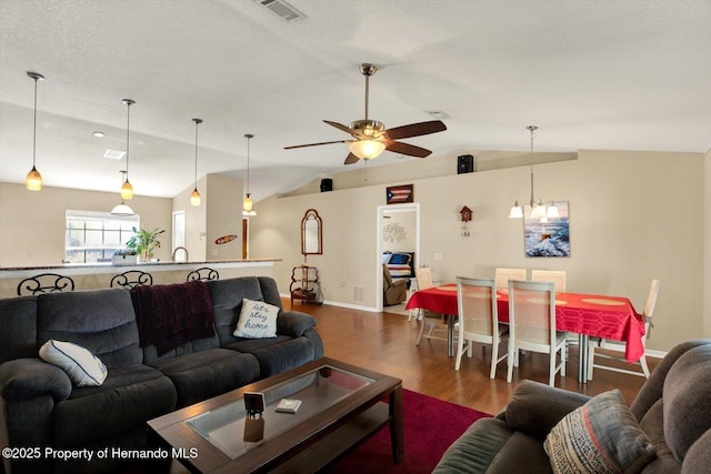 living room with visible vents, wood finished floors, baseboards, ceiling fan, and vaulted ceiling