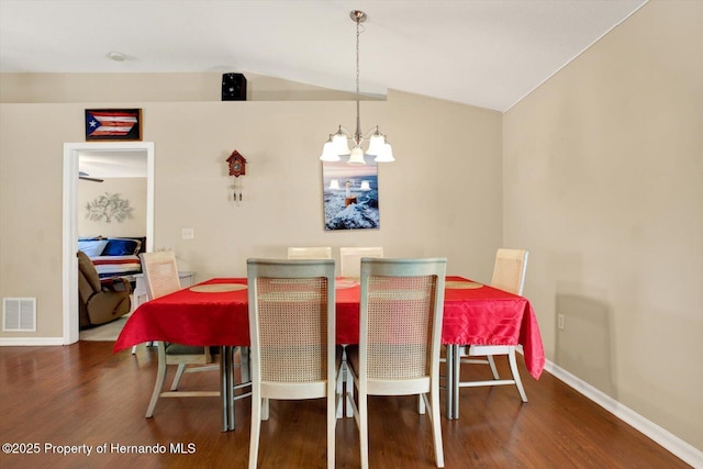 dining room featuring visible vents, a notable chandelier, wood finished floors, and vaulted ceiling