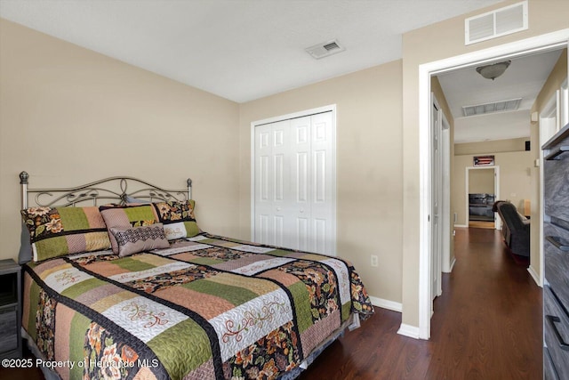 bedroom with wood finished floors, visible vents, and a closet