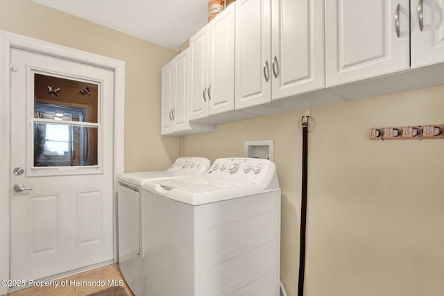 clothes washing area featuring washing machine and clothes dryer, cabinet space, and light tile patterned flooring