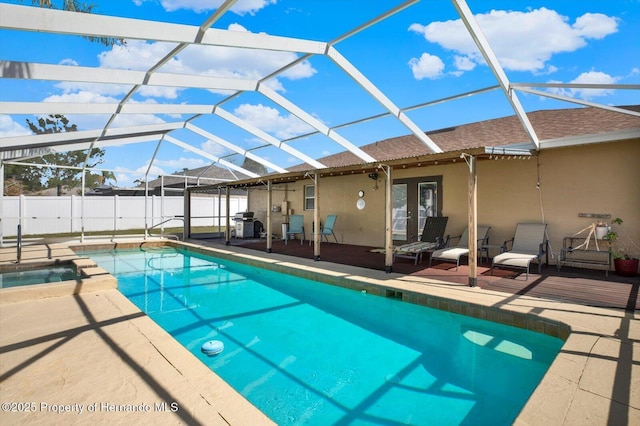 view of swimming pool with glass enclosure, a patio, fence, a pool with connected hot tub, and a grill