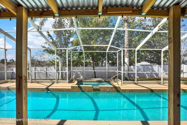 view of swimming pool featuring a patio area, fence, a pool with connected hot tub, and a lanai