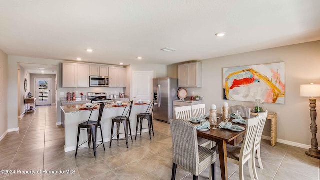 kitchen featuring an island with sink, appliances with stainless steel finishes, a breakfast bar area, gray cabinets, and recessed lighting