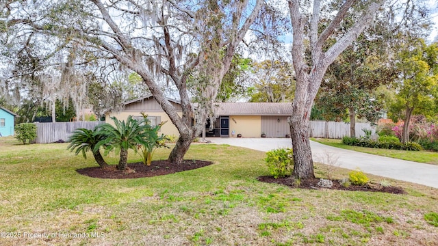 ranch-style home with concrete driveway, a front yard, and fence