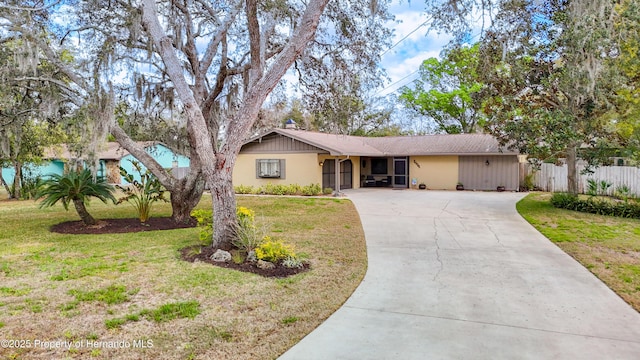 ranch-style home with driveway, a front lawn, and fence