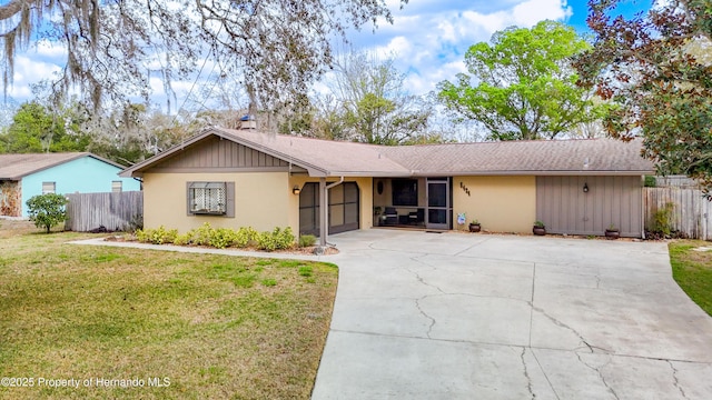 single story home featuring concrete driveway, fence, a front lawn, and an attached garage