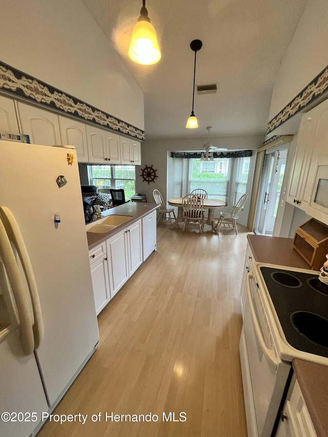 7441 Baywood Forest Cir, Spring Hill, FL 34606 - kitchen featuring white appliances, white cabinets, light wood-style floors, a sink, and decorative light fixtures