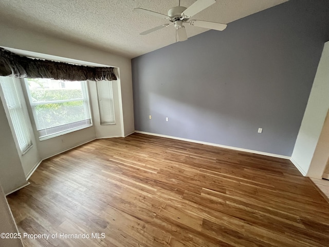 7441 Baywood Forest Cir, Spring Hill, FL 34606 - unfurnished room featuring a textured ceiling, wood finished floors, a ceiling fan, and baseboards