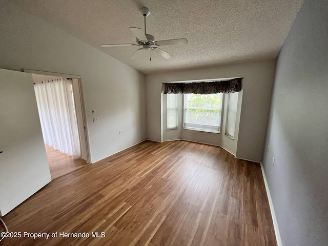 7441 Baywood Forest Cir, Spring Hill, FL 34606 - spare room with wood finished floors, ceiling fan, a textured ceiling, and vaulted ceiling