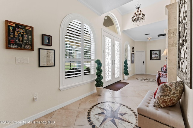 foyer entrance featuring ornamental molding, tile patterned flooring, baseboards, and an inviting chandelier