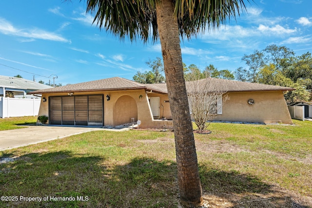 view of front facade featuring driveway, a front yard, fence, and stucco siding