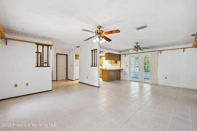 unfurnished living room with a textured ceiling, light tile patterned floors, visible vents, a ceiling fan, and french doors