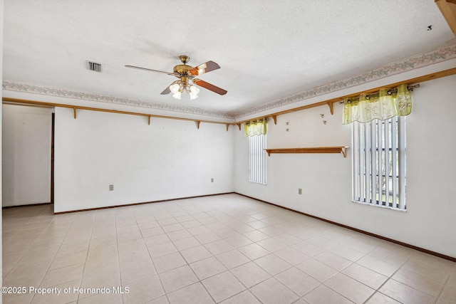 spare room with light tile patterned floors, visible vents, a ceiling fan, a textured ceiling, and baseboards