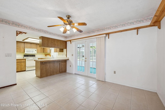 kitchen featuring a textured ceiling, a peninsula, white appliances, light countertops, and french doors