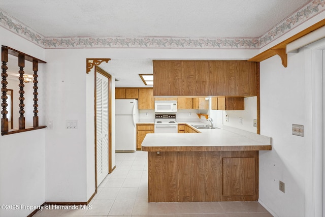 kitchen with white appliances, a peninsula, light countertops, a sink, and light tile patterned flooring