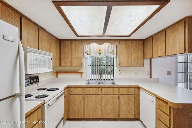 kitchen featuring light countertops, brown cabinetry, a sink, white appliances, and a peninsula