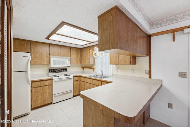 kitchen featuring a peninsula, white appliances, a skylight, a sink, and light countertops