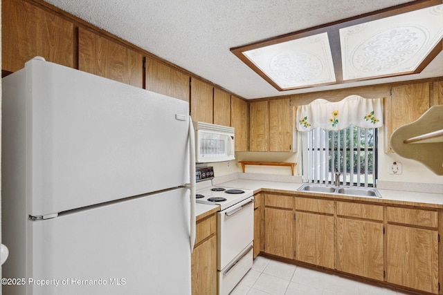 kitchen with a textured ceiling, light tile patterned floors, white appliances, a sink, and light countertops