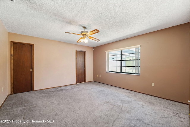 empty room with carpet floors, ceiling fan, a textured ceiling, and baseboards