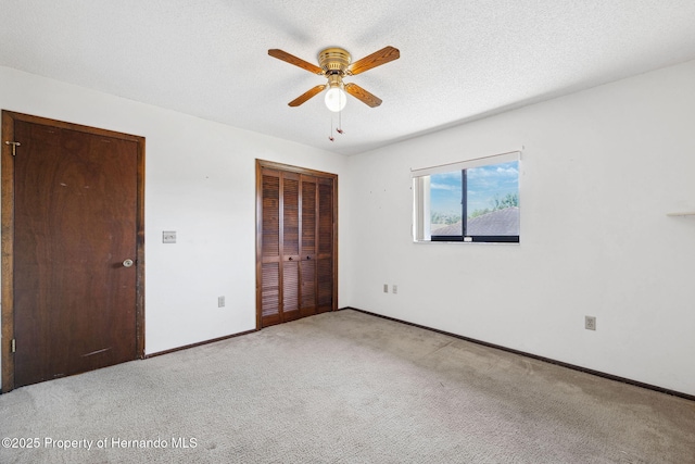 unfurnished bedroom with a closet, light carpet, a textured ceiling, and baseboards