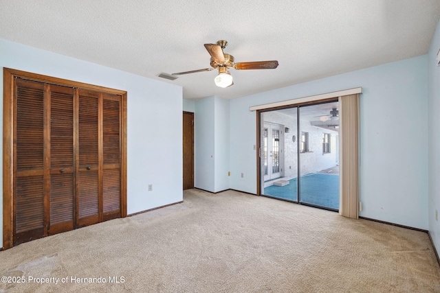 unfurnished bedroom featuring a textured ceiling, carpet flooring, visible vents, and access to exterior