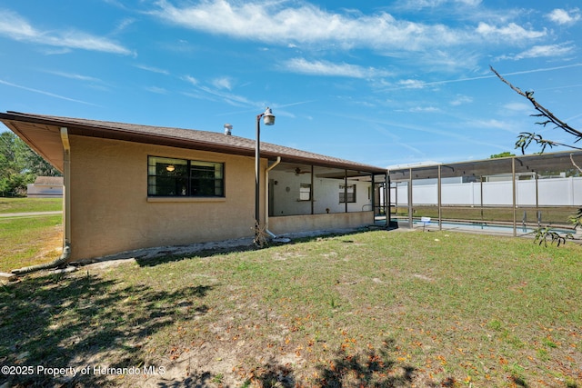 back of property with a fenced in pool, a yard, stucco siding, fence, and a lanai