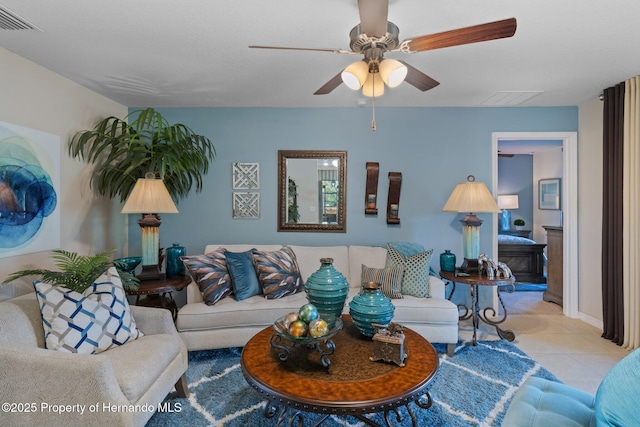 living room featuring tile patterned flooring, visible vents, and a ceiling fan