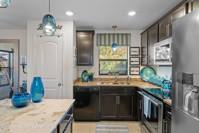 kitchen featuring appliances with stainless steel finishes, a healthy amount of sunlight, a sink, and light stone countertops